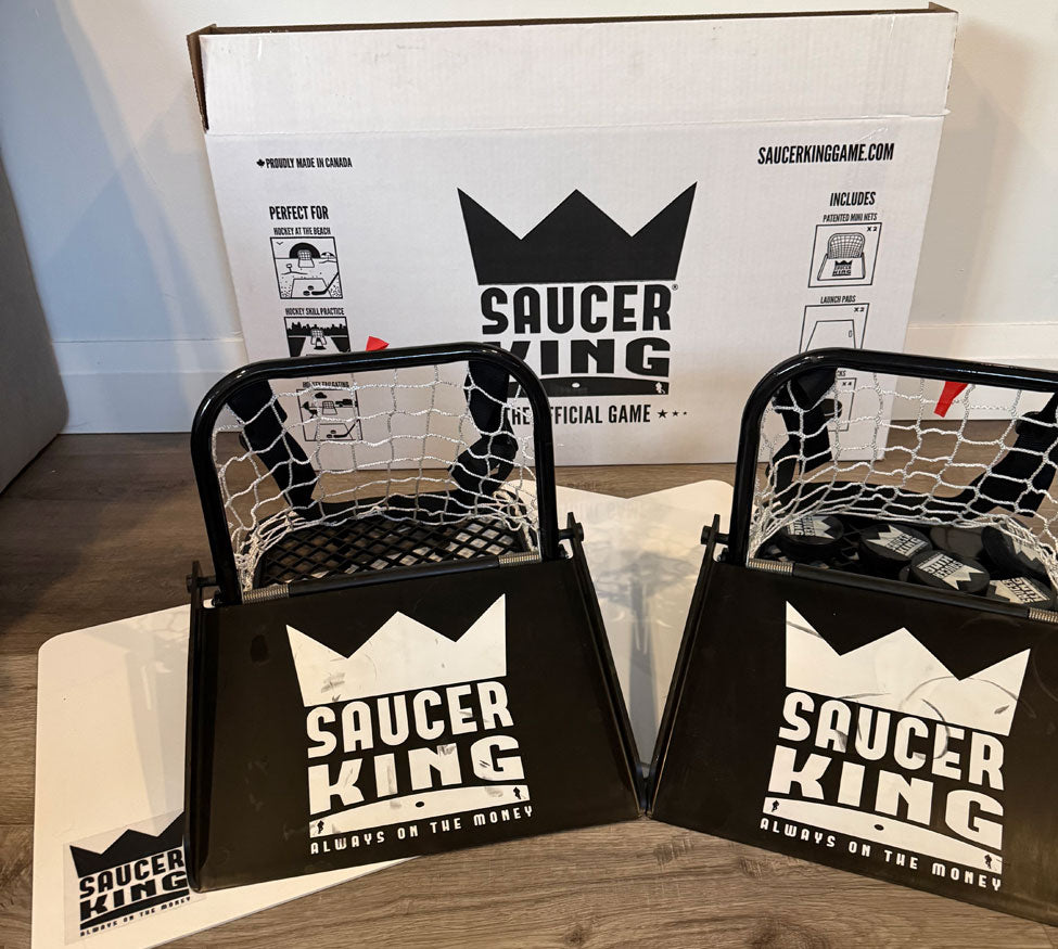 Two 'Saucer King' game sets with packaging in the background.